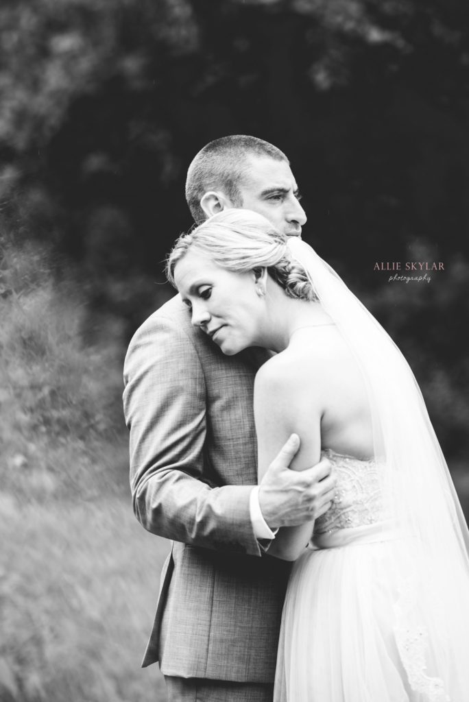 bride and groom embrace in a field