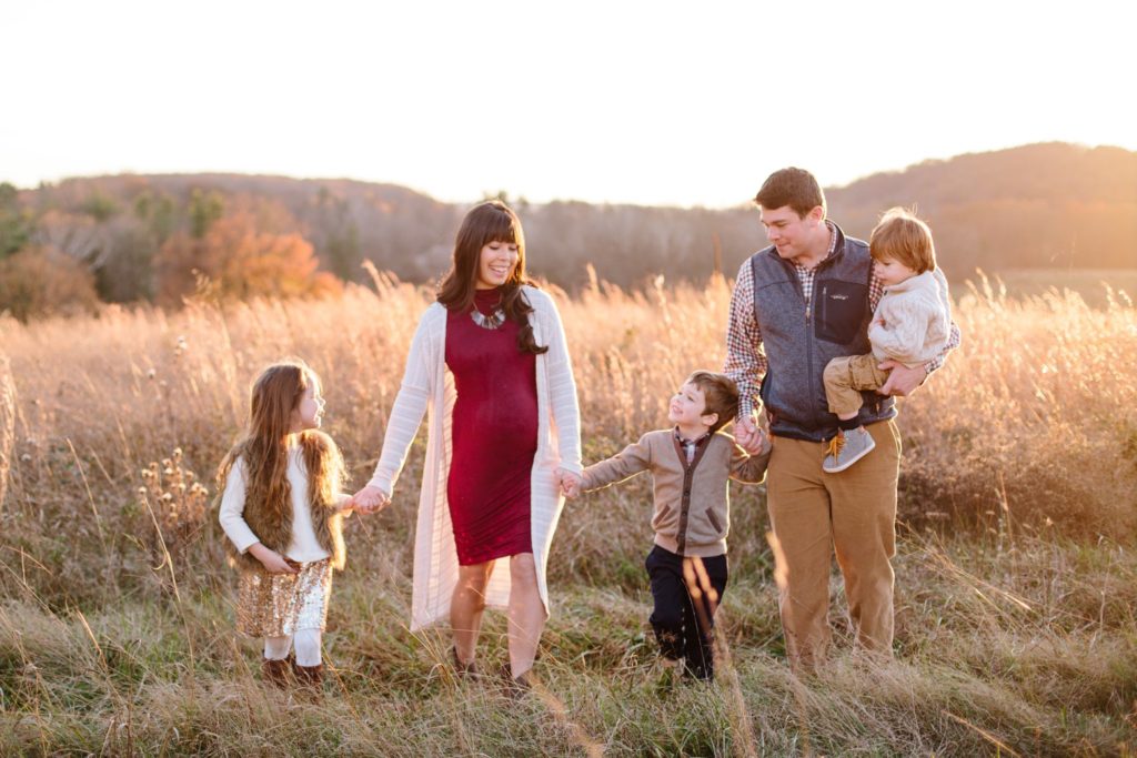 family walks through a field at valley forge national park during their family session