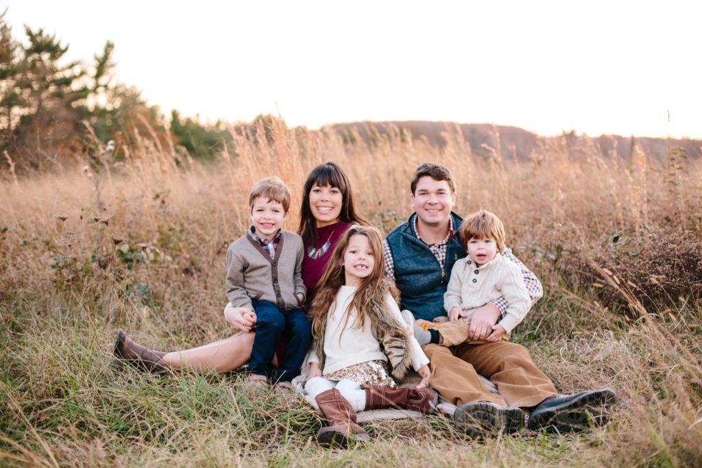 family poses in a field at sunset at valley forge national park during their family portrait session