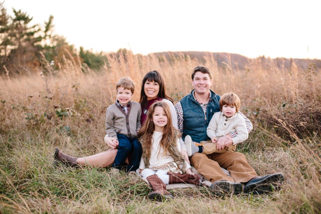 family poses in a field at sunset at valley forge national park during their family portrait session
