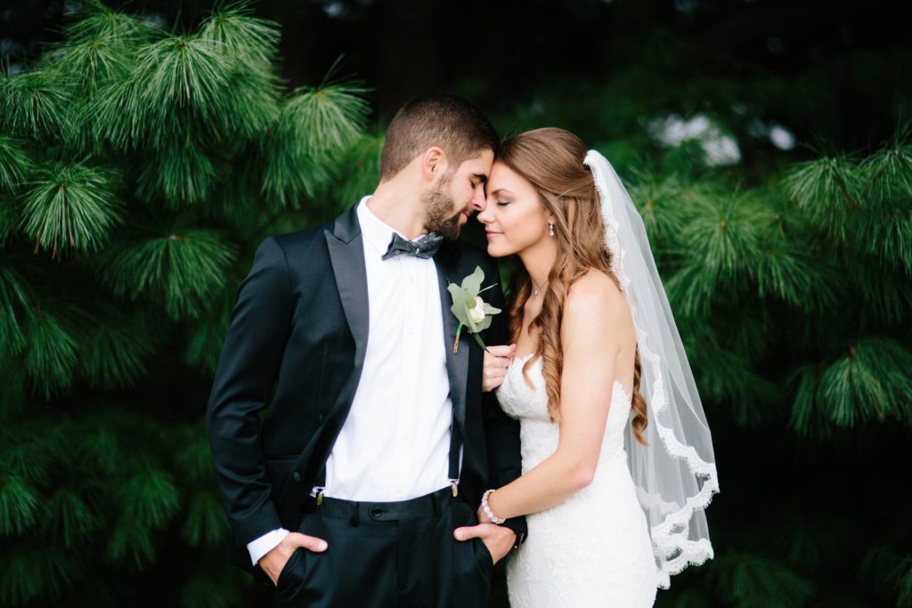 bride and groom share romantic kiss in front of pine tress at rose bank winery photographed by allie skylar photography 