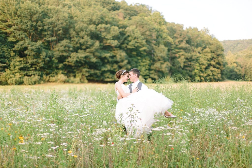 bride and groom embrace in a field of wildflowers at the brn at greenwood in northeast PA