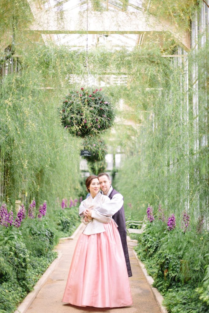 korean bride and groom pose in the halls of longwood gardens wearing their traditional hanboks