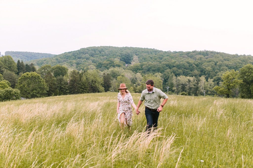 bride and groom run through a field in downingtown pennsylvania during their engagement session