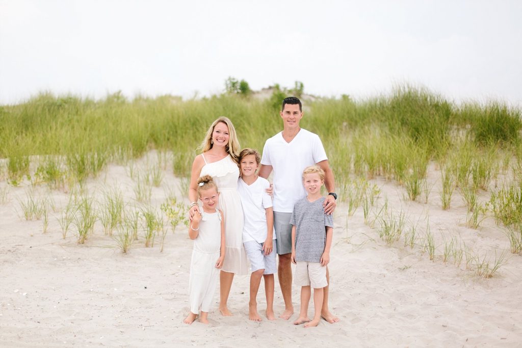 family of five pose on the beach in ocean city new jersey for their family photos