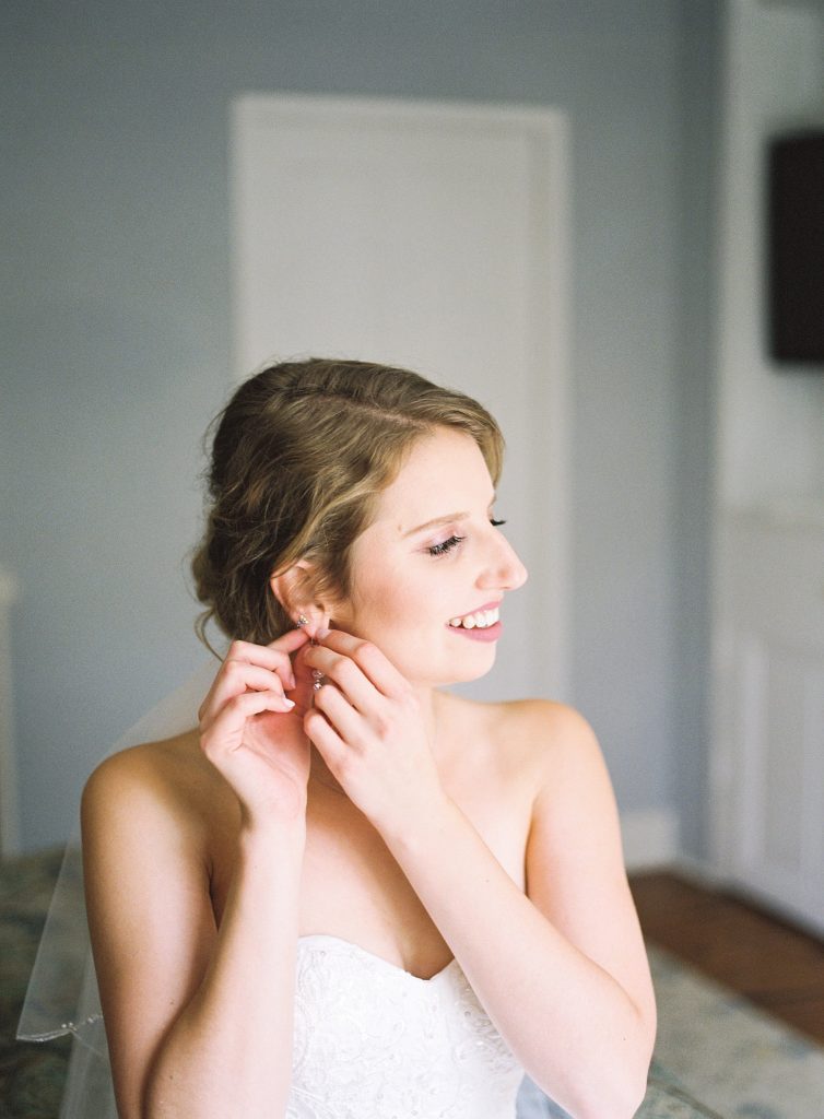 bride puts on her earrings before her wedding at grace winery