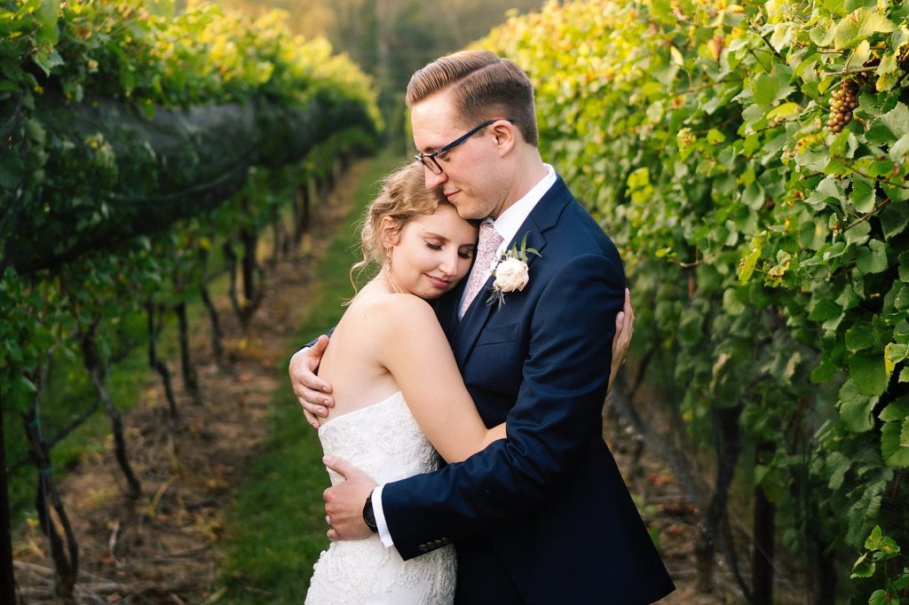 bride and groom embrace in the vineyards at Grace Winery after their wedding