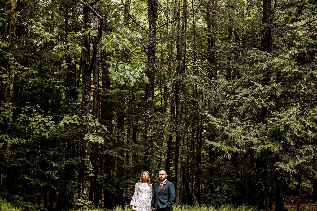 bride nd groom stand in the woods in the rain at their wedding at pump house b&b in bloomsburg pa