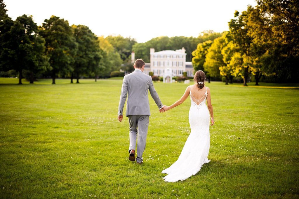 Bride and groom stroll towards the pen ryn mansion on their wedding day
